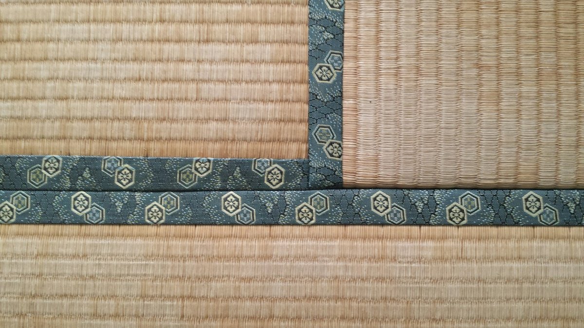 Gros plan sur des tatamis en jonc tressé, séparés par une bande de tissu bleu à motifs